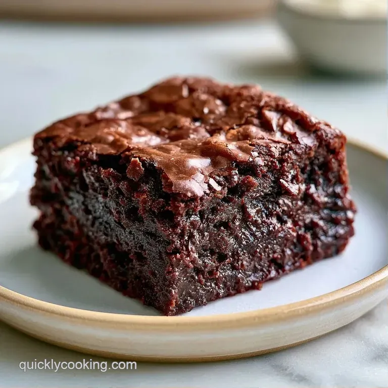 A neat square of dark, dense chocolate cake topped with a dollop of whipped cream and a fresh raspberry.